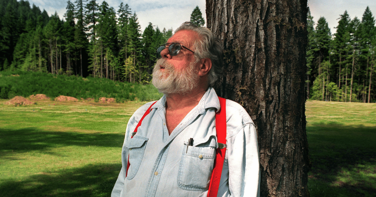 Jim Baker leans against the trunk of a tree